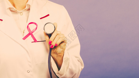 粉色礼物盒妇女为健康而斗争乳腺癌肿瘤概念粉色丝带和蓝听诊器白医疗围裙制服生持有疗设备背景