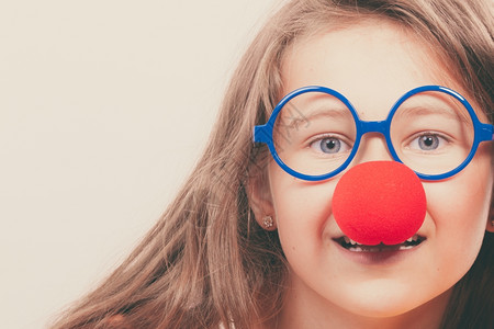 带眼镜的小丑红鼻子的小女孩准备玩吧狂欢节时间背景