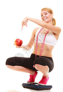 快乐的年轻女孩上面有衡量大小的胶带拿着苹果缩小和饮食健康的生活方式营养概念孤立于白种背景图片