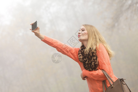 快乐的时装女郎在公园拍自快乐的时装女郎在秋天公园拍自照片图片