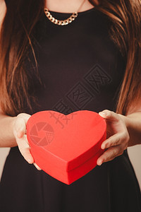 女人握着心爱的帮助和慈善女人握着红心盒在工作室的礼物图片