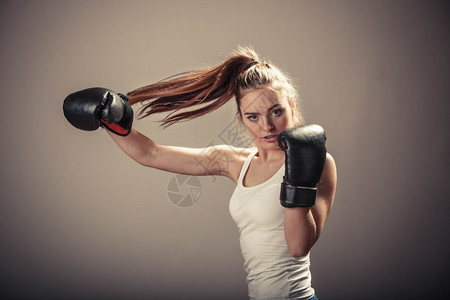 精力充沛的年轻女子用拳击手套打架与对手拳击运动和体力建设强健的年轻女子打敌有马尾的女子戴白箱顶和拳击手套图片