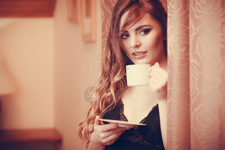 感女在家里喝热咖啡饮料感女穿内衣在家中用窗帘喝咖啡具有热刺激饮料的年轻女孩保持清醒咖啡因能Instagram过滤器图片
