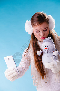 穿着耳毛和白色衣的迷人女孩穿着蓝色工作室冬季时装图片