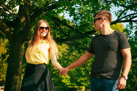 快乐的情侣戴着墨镜牵手在公园里图片