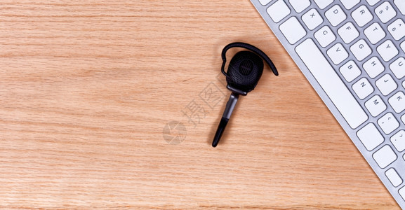 红色橡树桌面上有计算机键盘的无线耳顶端视图设备左侧复制空间图片