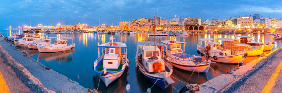 希腊克里特的拉翁岛腊的拉克里翁岛旧港的全景在黄昏蓝色时刻有渔船和码头的表面运动模糊不清图片