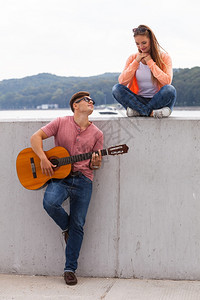 爱浪漫关系音乐概念快情侣在海岸度过时间年轻男孩在给女弹吉他图片
