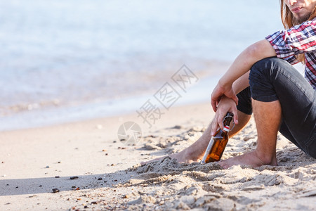 一个人在户外海滩上喝着酒瓶图片