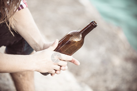 男在户外用酒瓶的男手在户外喝着酒瓶男在户外的海边喝着酒瓶图片