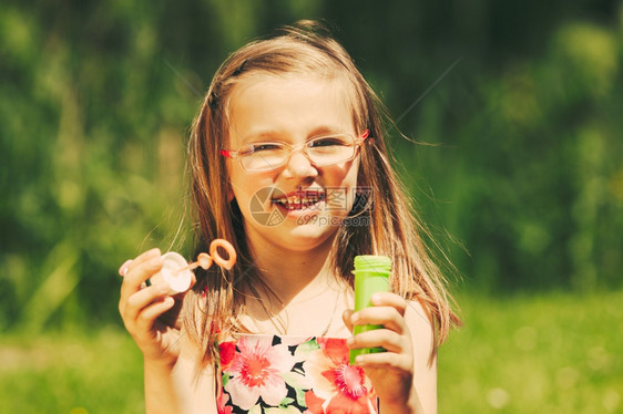 快乐的小女孩在户外吹泡微笑的小女孩在户外吹泡快乐的小孩在公园玩得开心图片