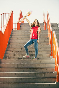 城市滑板女孩穿着的酷长发女孩站在城市楼梯上着滑板图片