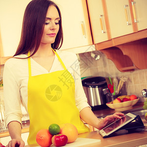 厨房的年轻女家庭主妇在餐桌上用平板电脑看食谱健康饮烹饪素饮和技术概念图片