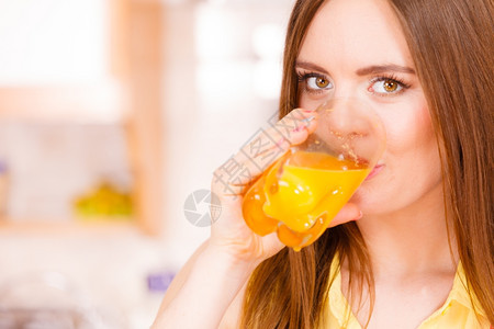家里厨房的女人喝着新鲜自制橙汁饮料健康食素减肥和人的概念图片
