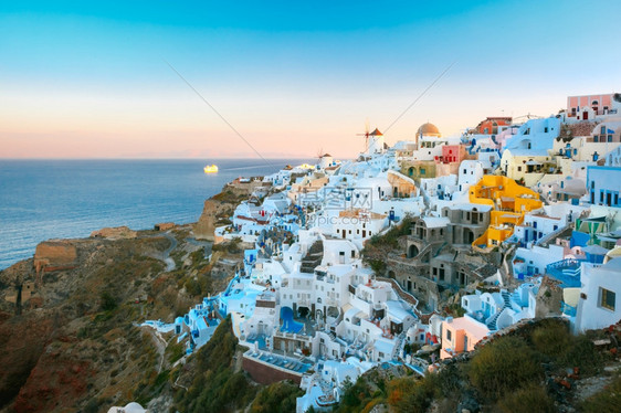 希腊圣托里尼岛的奥亚老城或伊白房子和日落时风车图片