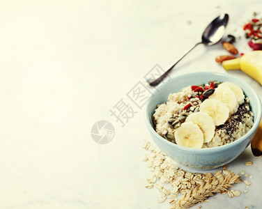 健康早餐家里在白色的陶瓷碗里煮了燕麦粥果汁南瓜和辣椒种子图片