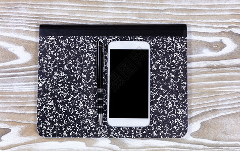 笔记本和手机在淡白色木制桌面上显示的阴影视图背景图片