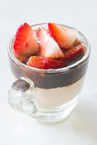 巧克力Mousse沾满了白底玻璃杯中的草莓果图片