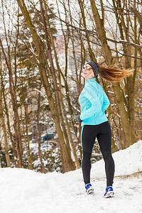 女孩在冰冻的公园里慢跑在雪和树之间健康身自然时尚概念图片