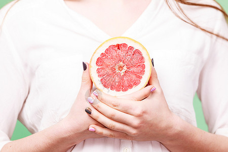 妇女手中握着一半的葡萄果柑橘水健康饮食减肥脱毒概念图片