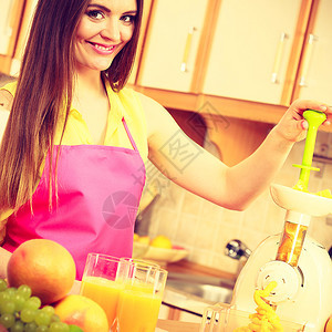 厨房的年轻女家庭主妇在果汁机中制造新鲜橙汁准备营养维生素包装饮料图片