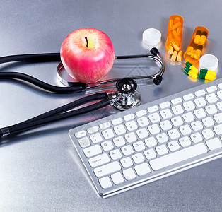 用电脑键盘药丸瓶子和苹果检查桌上的医学听诊器图片