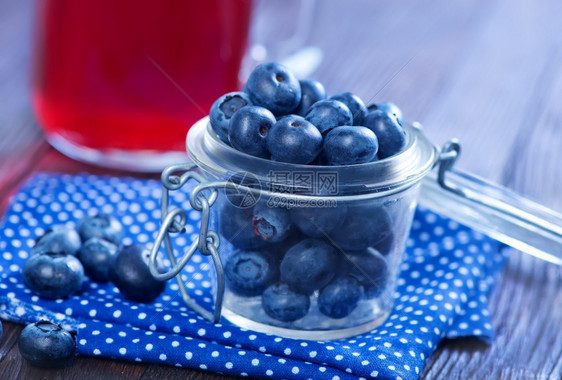 玻璃和桌子上新鲜的蓝莓图片