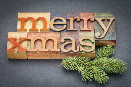 圣诞快乐贺卡用古老的纸质印刷木制贺卡成在石块上加树枝图片