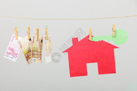 红房子绿色钥匙和钞票现金挂在灰色背景的洗衣线上出售和购买家庭概念图片