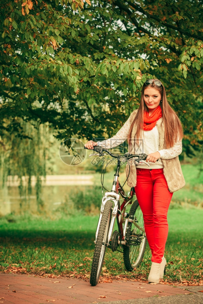 年轻女子在户外的森林公园推着自行车