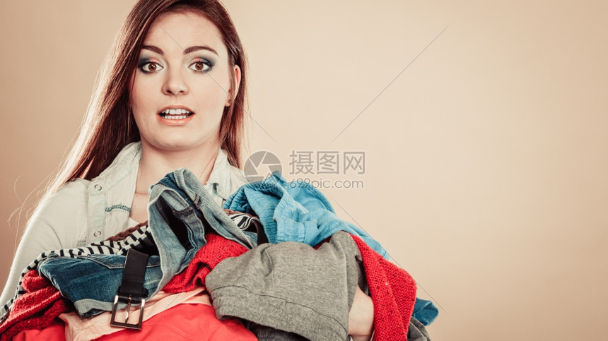 年轻妇女拿着一堆衣服每天在家庭洗衣和熨服中例行公事年轻女孩拿着一堆彩色的衣服图片