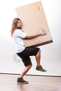 送货员拿着纸盒送货服务和概念年轻男邮递员拿着重的立方体包装箱图片