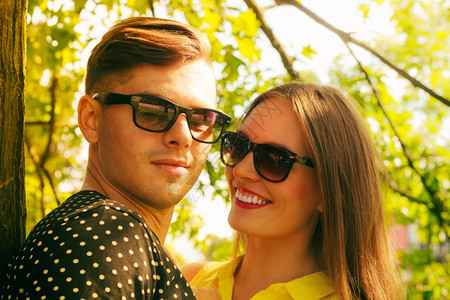 快乐的年轻情侣戴着墨镜在夏日公园露天约会图片