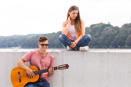 在海边弹吉他给女友听的男子背景图片