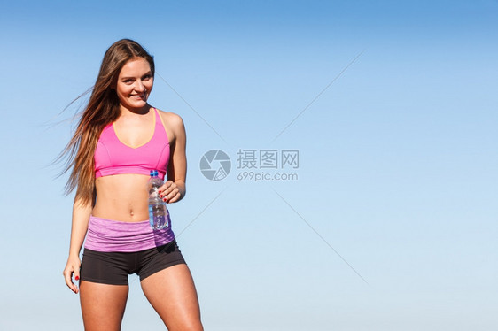 运动穿服的妇女休息从塑料瓶中补充水在户外运动锻炼后休息图片
