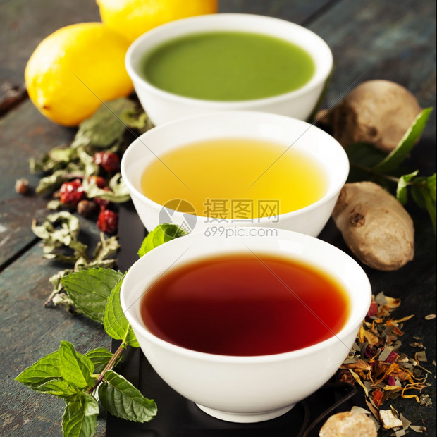 茶叶概念陶瓷碗和木制背景原料中不同种类的茶叶黑绿色和红图片