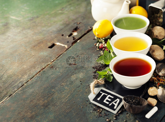 茶叶概念陶瓷碗和木制背景原料中不同种类的茶叶黑绿色和红图片