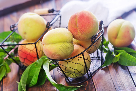 篮子和木制桌上的新鲜桃子图片