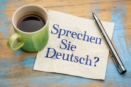 至少还有你你会说德语吗手写在餐巾纸上还有一杯咖啡背景