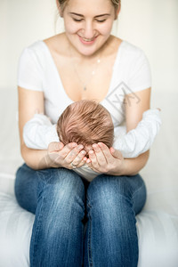 母亲的肖像坐在床上抱着她三个月大的婴儿头部图片