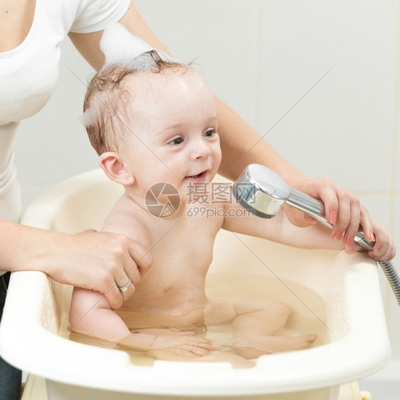 母亲在洗手间澡可爱婴儿的近照图片