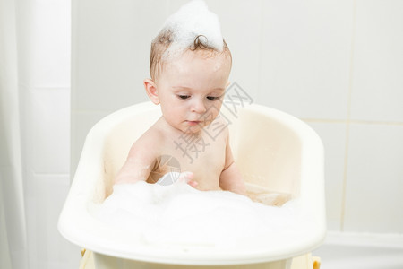 在洗澡时玩泡沫的可爱小男孩肖像图片
