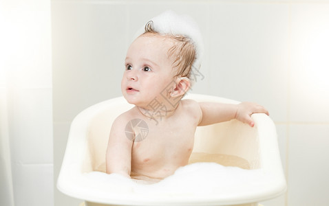 坐在洗手间泡沫里的小可爱男孩背景图片