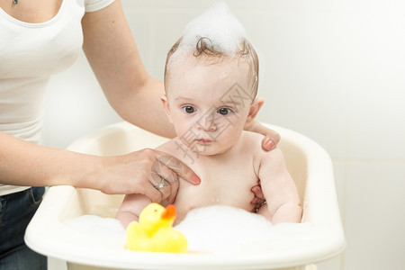 在洗澡时玩黄色橡皮鸭的可爱小男孩肖像图片