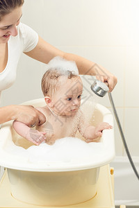 可爱小男孩在洗澡时用淋浴头的肖像图片