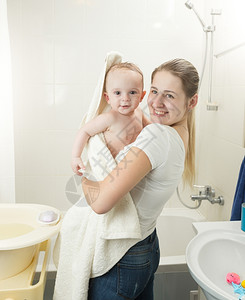 微笑的母亲在洗完澡后用毛巾覆盖婴儿的肖像图片