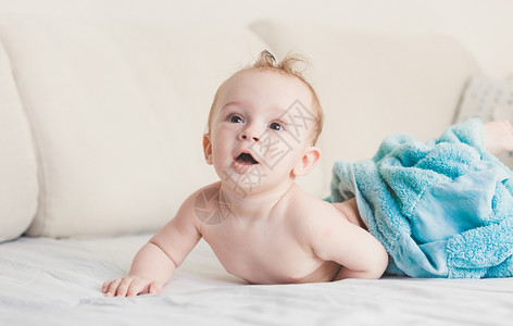 美丽的九个月蓝毛巾的男孩睡在床上白单和图片