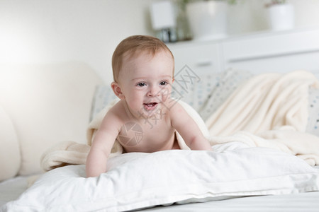 9个月大的婴儿男孩爬在床上枕头图片
