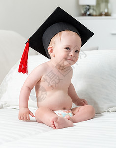 穿着尿布和毕业帽的可爱笑男孩肖像图片