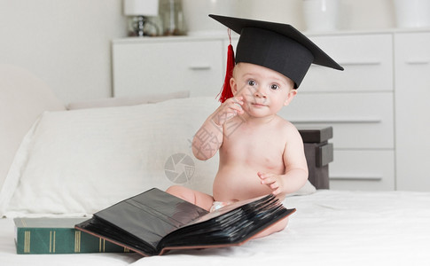 穿着毕业帽子的聪明小男孩肖像假扮成书本图片